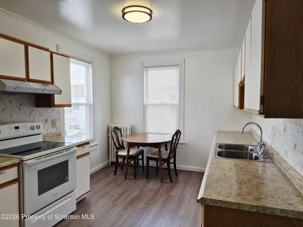 a kitchen with a stove a sink and a dining table with wooden floor