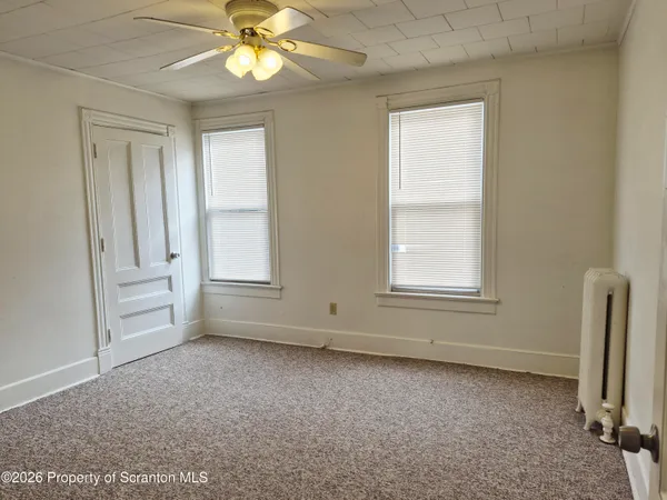 an empty room with windows and fan