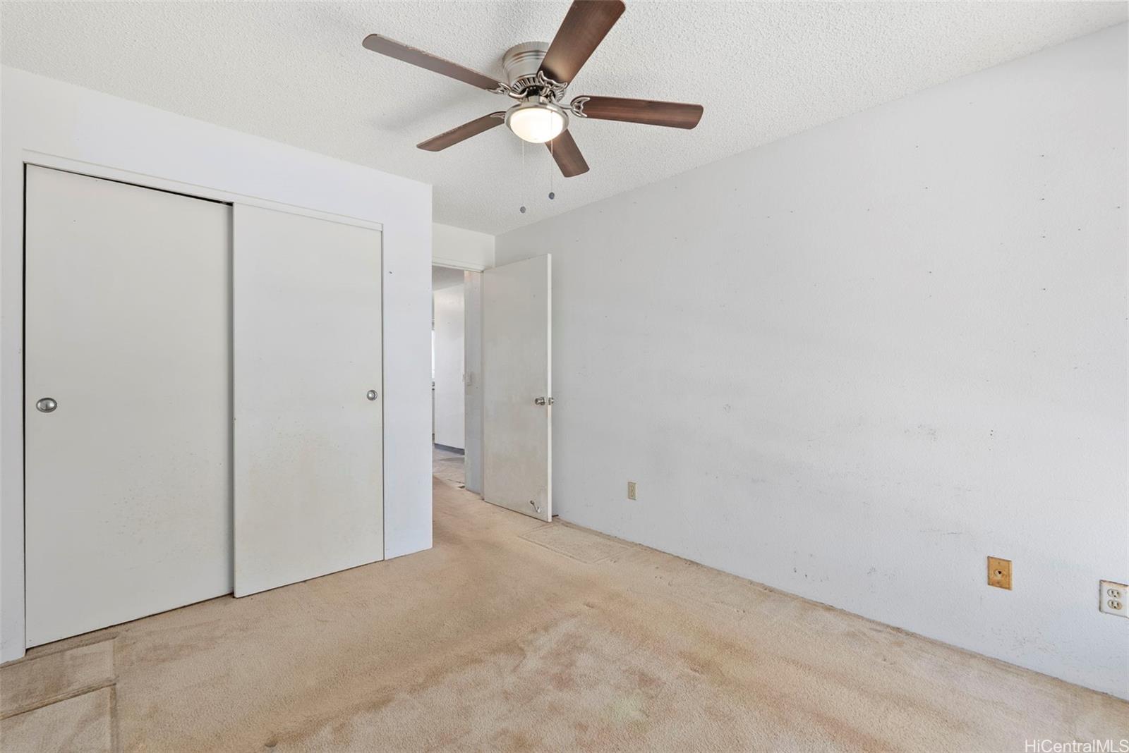 94-201 Lumiaina Place, Unit E202 Waipahu, HI 96797 - Photo 13 of 25 an empty room with a ceiling fan and a window