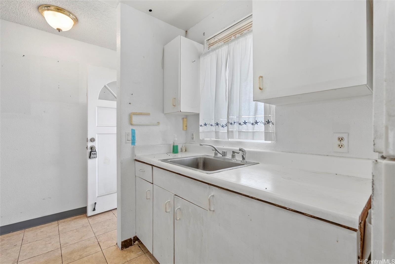 94-201 Lumiaina Place, Unit E202 Waipahu, HI 96797 - Photo 9 of 25 a kitchen with a sink cabinets and window