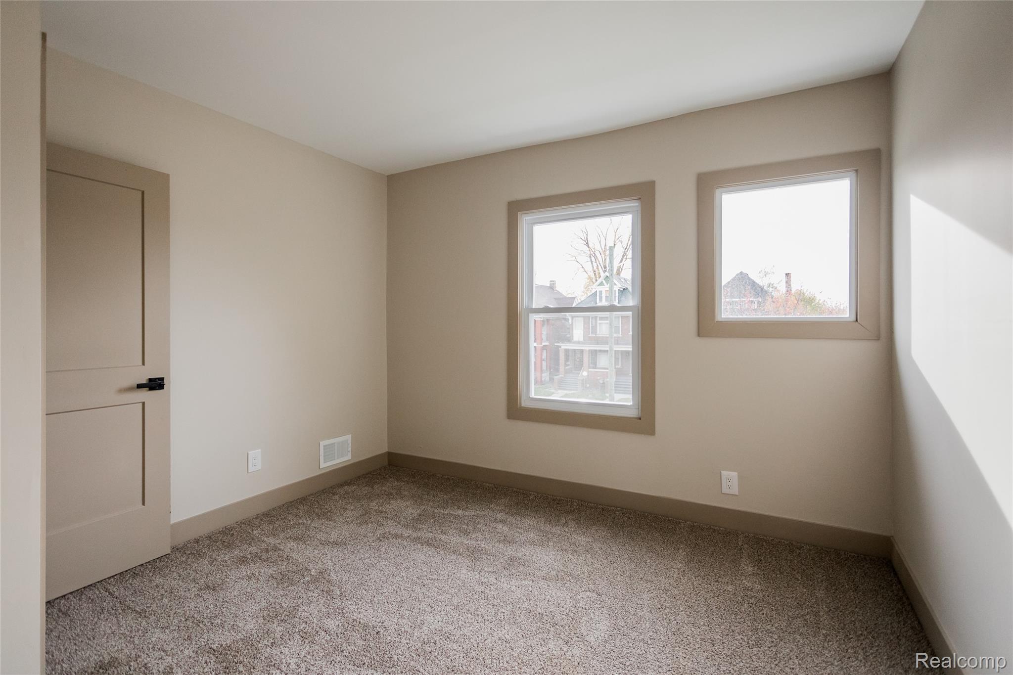 2630 Harding Street Detroit, MI 48214 - Photo 19 of 30 Neutral wall paint, plush carpet flooring, two windows, modern flat-panel door with black hardware, and coordinating baseboards