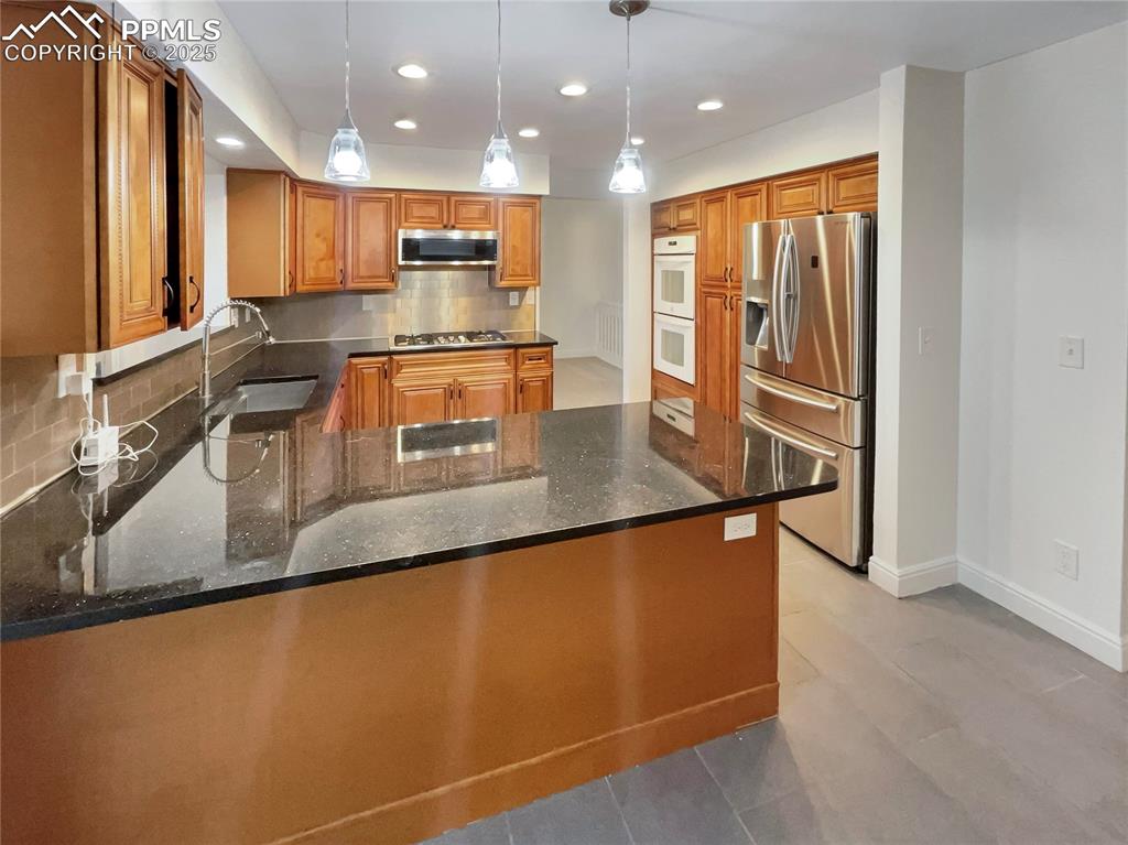 570 Ore Cart Way Monument, CO 80132 - Photo 10 of 22 a kitchen with stainless steel appliances granite countertop a refrigerator a stove and a sink with wooden floor