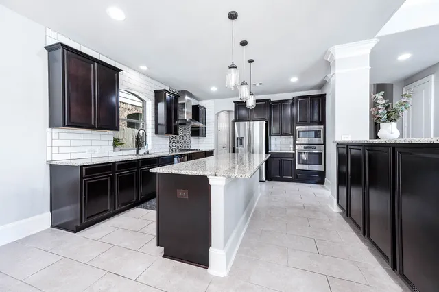 a kitchen with stainless steel appliances granite countertop a refrigerator a oven and a sink with large countertops