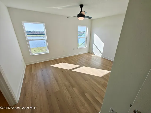 an empty room with wooden floor and windows