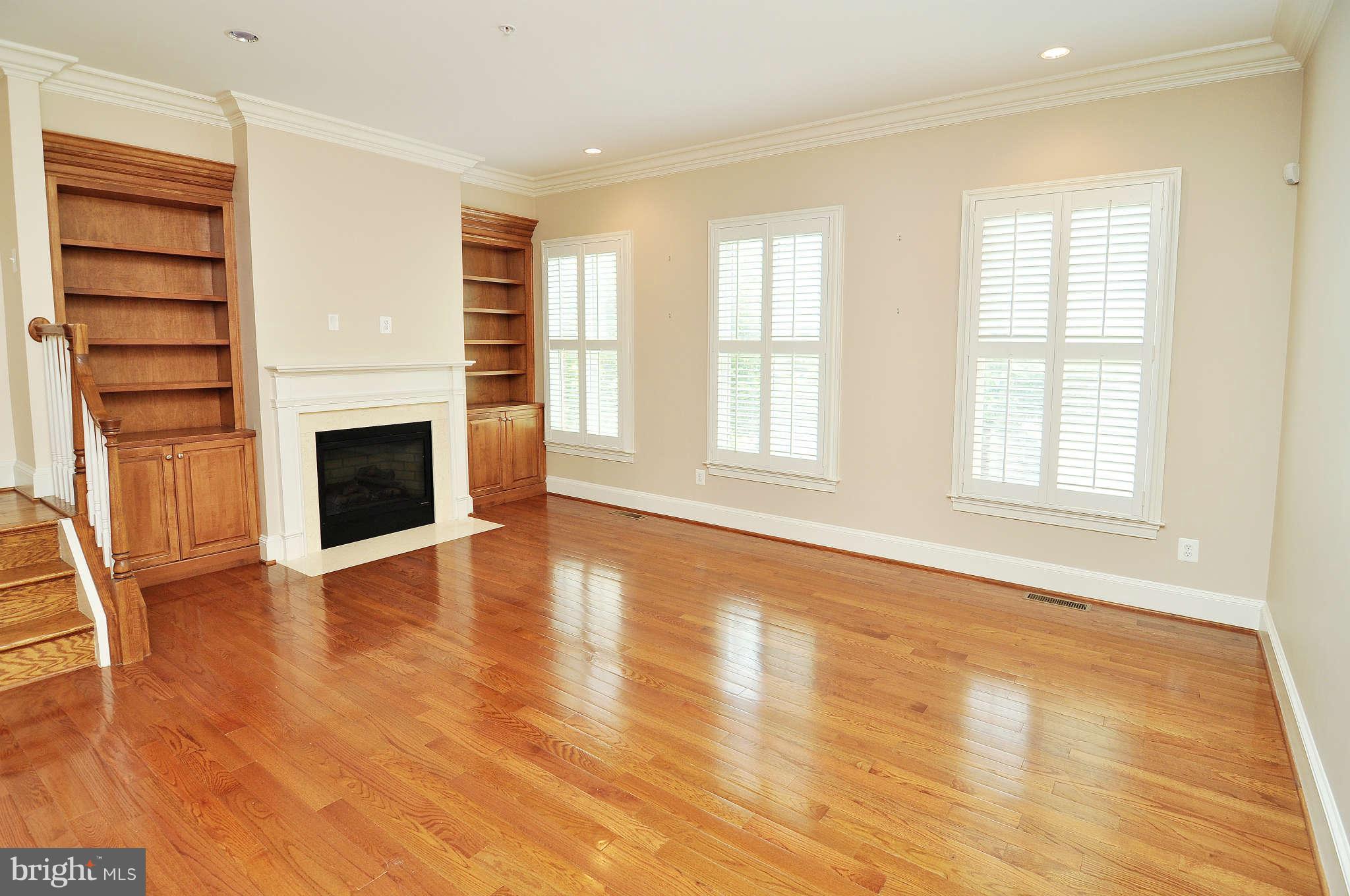 719 Carpenter Road Alexandria, VA 22314 - Photo 11 of 26 an empty room with wooden floor fireplace and windows