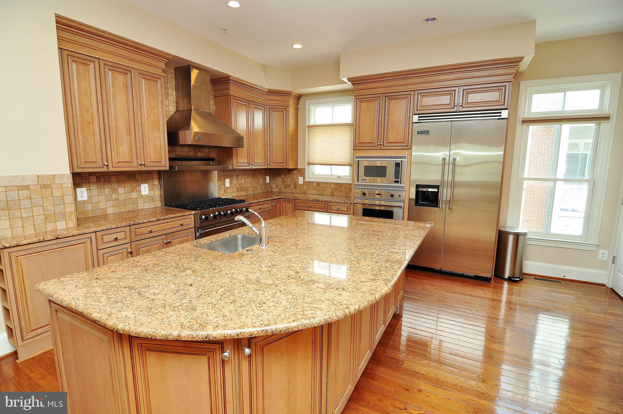 719 Carpenter Road Alexandria, VA 22314 - Photo 6 of 26 a kitchen with kitchen island granite countertop a sink a counter top space appliances and cabinets