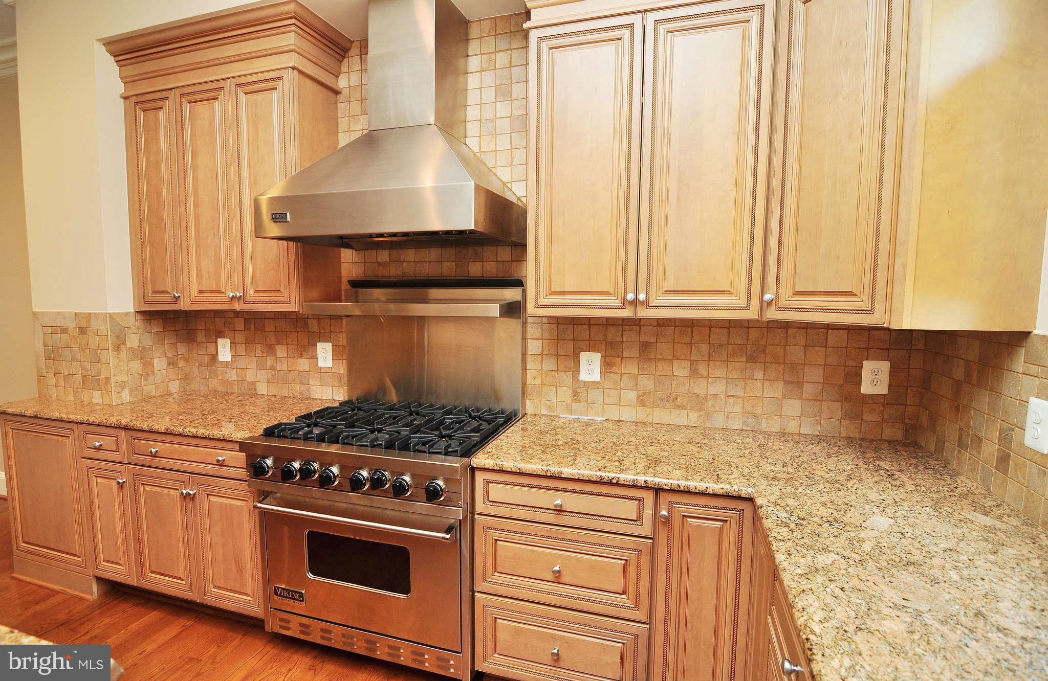 719 Carpenter Road Alexandria, VA 22314 - Photo 7 of 26 a kitchen with granite countertop a stove and a wooden cabinets