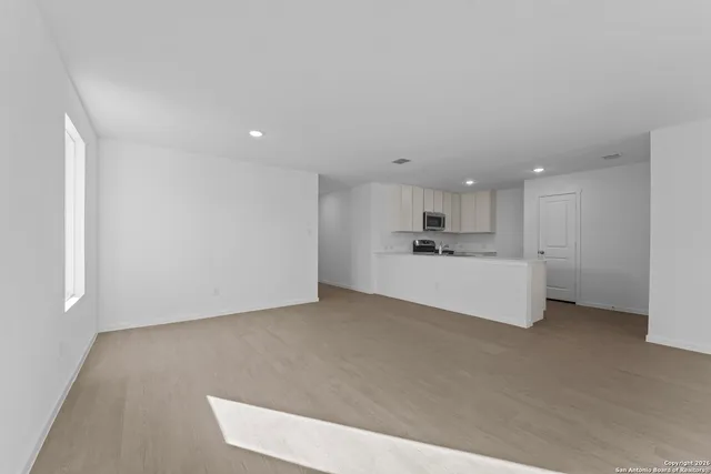 a view of kitchen with kitchen island a sink wooden floor and white cabinets