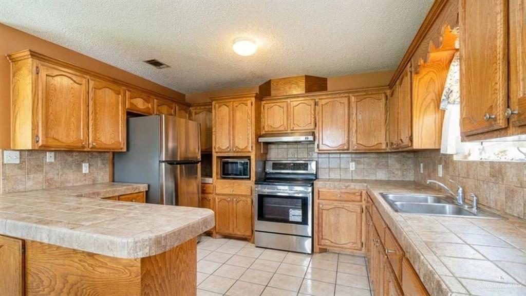1409 Valencia Avenue Pharr, TX 78577 - Photo 6 of 11 a kitchen with stainless steel appliances granite countertop a stove a sink and a microwave