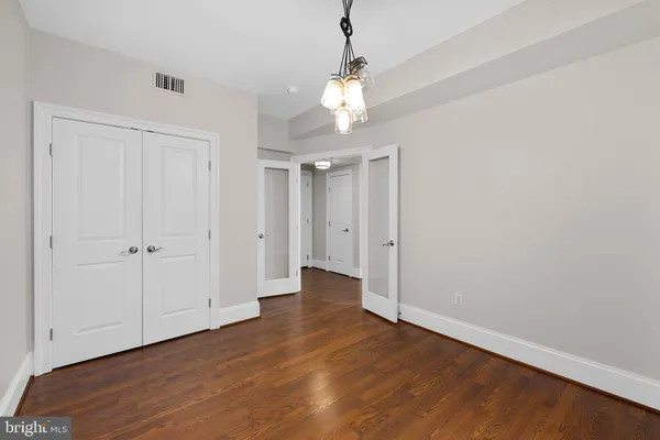 a view of an empty room with wooden floor and windows