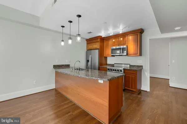 a kitchen with stainless steel appliances granite countertop a sink a stove and a wooden floors