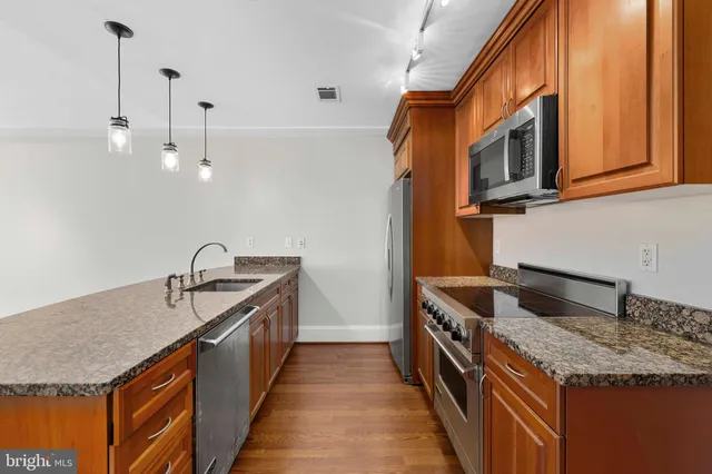 a kitchen with stainless steel appliances granite countertop a sink a stove and a wooden floor