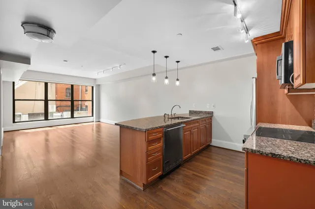 a large kitchen with stainless steel appliances granite countertop a stove a sink and a large window