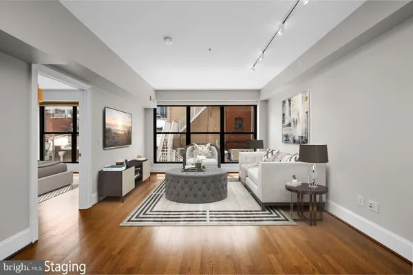 a living room with furniture a large window wooden floor and a rug