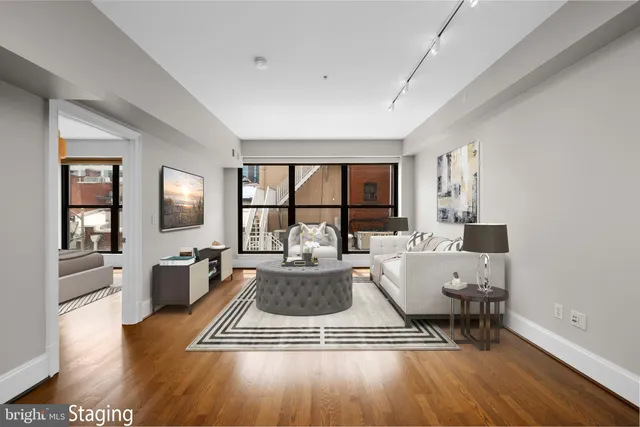 a living room with furniture a large window wooden floor and a rug