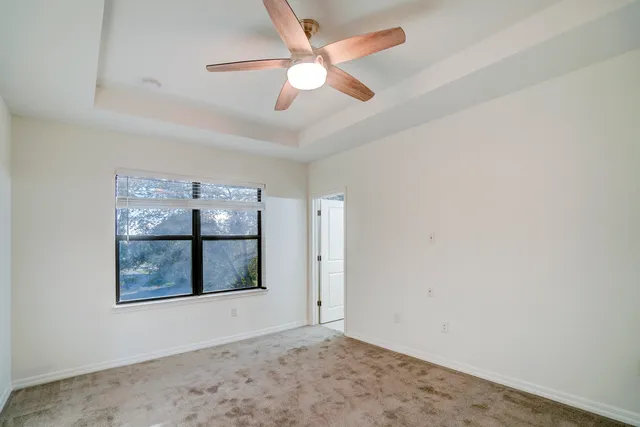 an empty room with windows and ceiling fan