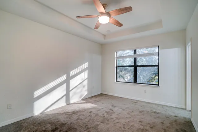 an empty room with windows and ceiling fan