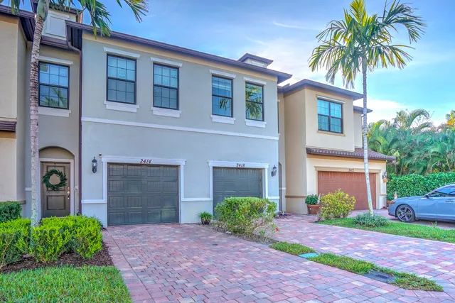 a front view of a house with yard and parking