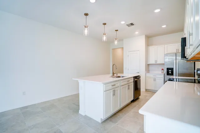 a large kitchen with stainless steel appliances a large counter top a stove and a sink