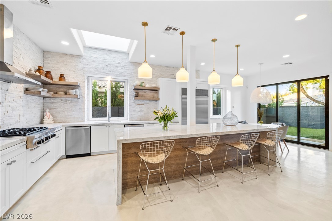 2000 Grouse Street Las Vegas, NV 89134 - Photo 24 of 89 An airy kitchen features an island with bar seating, white cabinetry, and skylights illuminating the space.