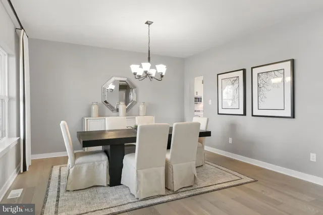 a dining room with wooden floor a chandelier a wooden table and chairs