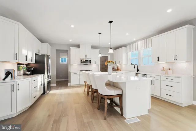 a large kitchen with white cabinets a sink a stove a dining table and chairs