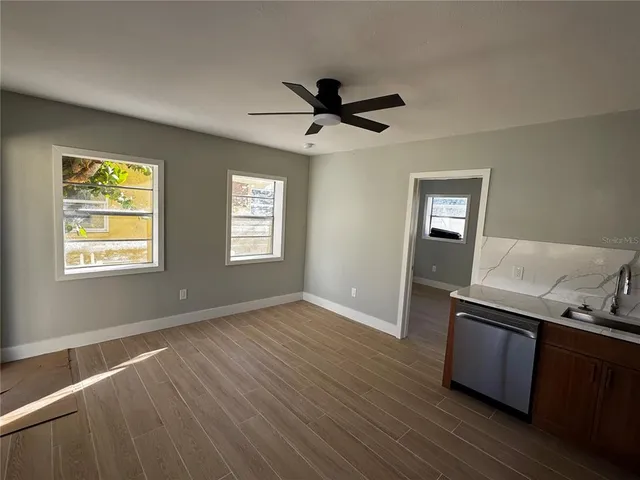 a view of an empty room with window and wooden floor