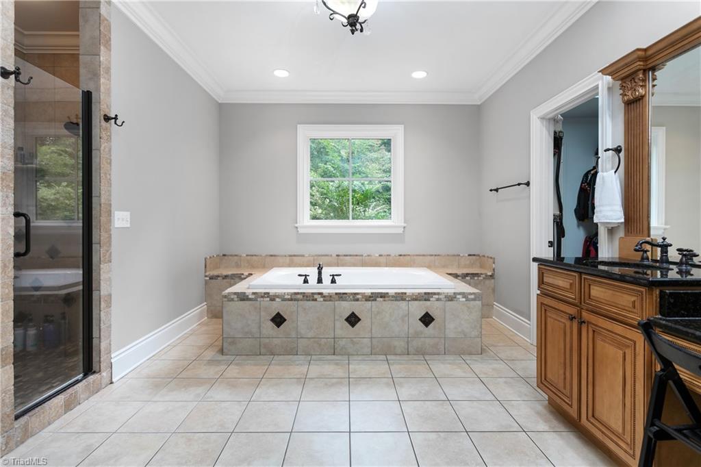 8302 Linville Oaks Drive Oak Ridge, NC 27310 - Photo 22 of 46 Spacious primary bathroom with soaking tub, two separate sink areas one with a vanity area and a large walk-in tiled shower.