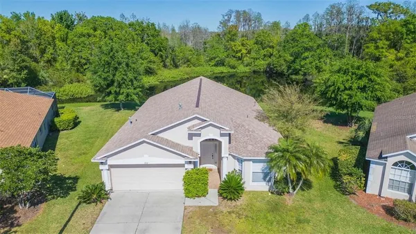an aerial view of a house with a big yard and large trees