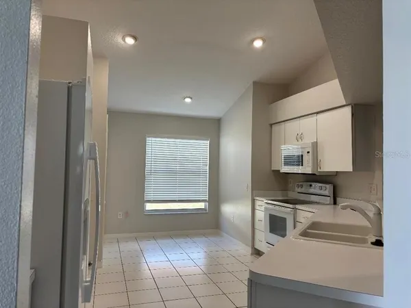 a kitchen with white cabinets and appliances