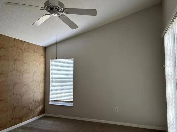 an empty room with windows and fan
