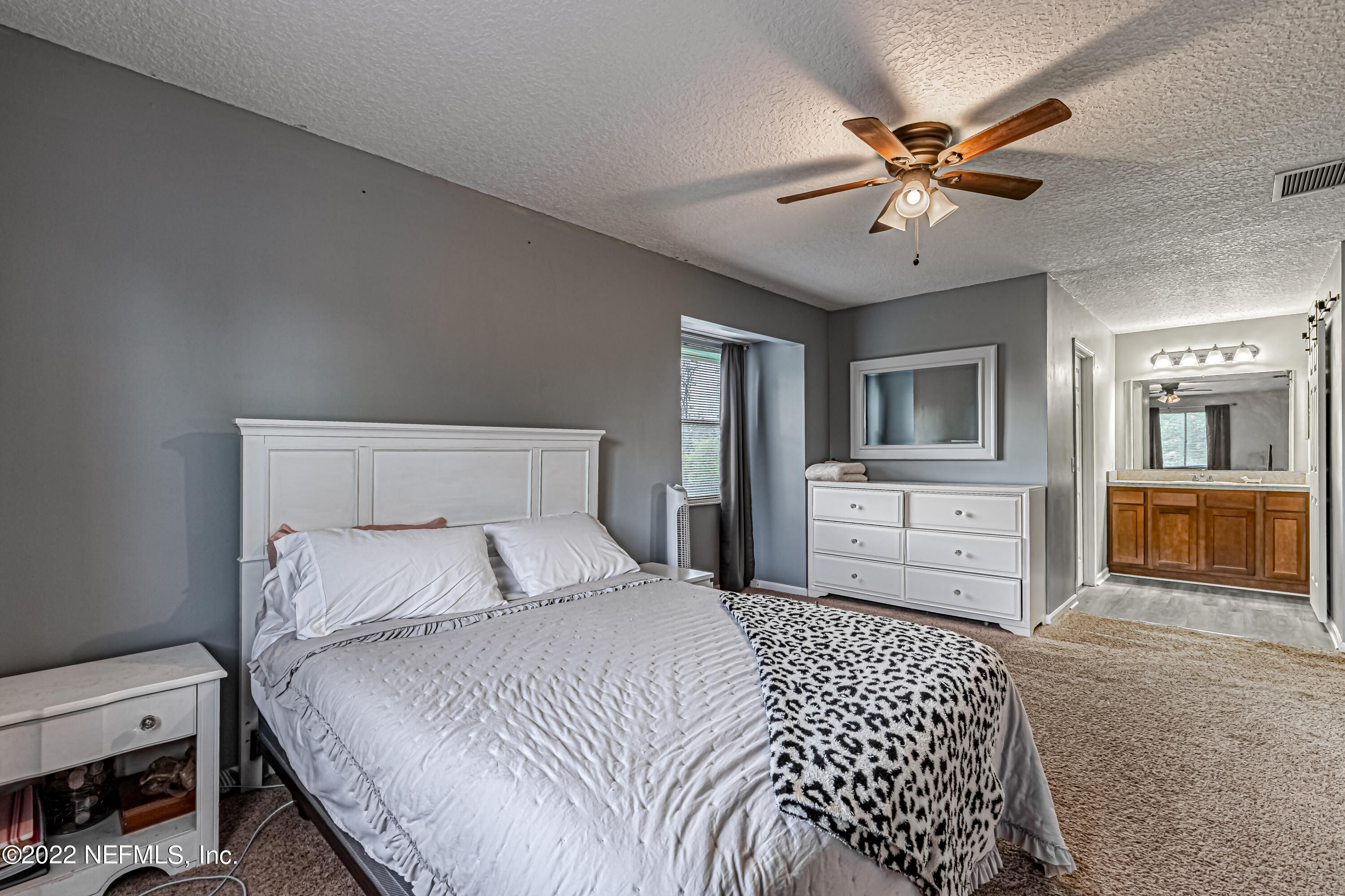 554 George Taylor Street Orange Park, FL 32073 - Photo 30 of 40 a bedroom with a large bed a chandelier with dresser and mirror