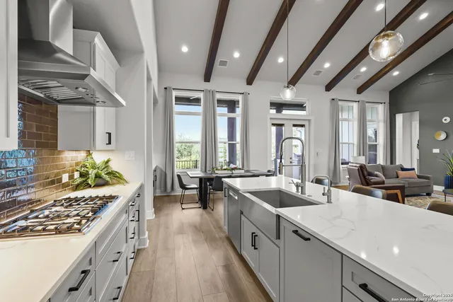a living room with furniture kitchen view and a wooden floor