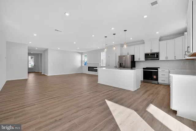 a view of kitchen with kitchen island stainless steel appliances refrigerator stove microwave and cabinets