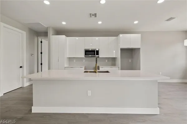 a large kitchen with kitchen island a stove a sink a refrigerator and white cabinets
