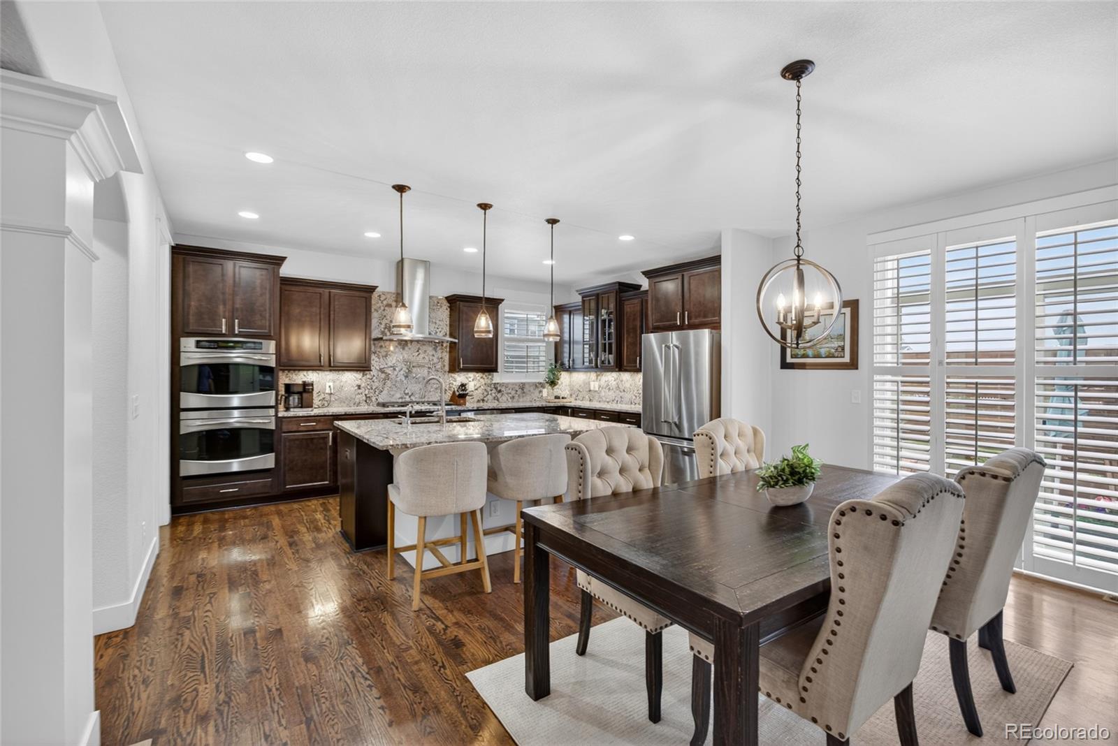 20554 East Shady Ridge Road Parker, CO 80134 - Photo 9 of 49 a kitchen with kitchen island a dining table chairs stainless steel appliances and cabinets