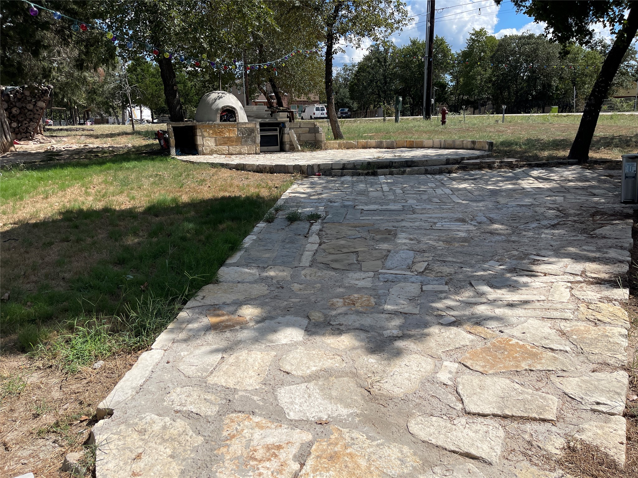 103 Azalea Avenue Elgin, TX 78621 - Photo 21 of 23 A spacious stone patio creates an inviting outdoor setting surrounded by mature shade trees.