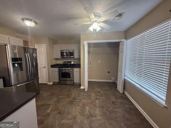 a kitchen with granite countertop a refrigerator and a stove top oven