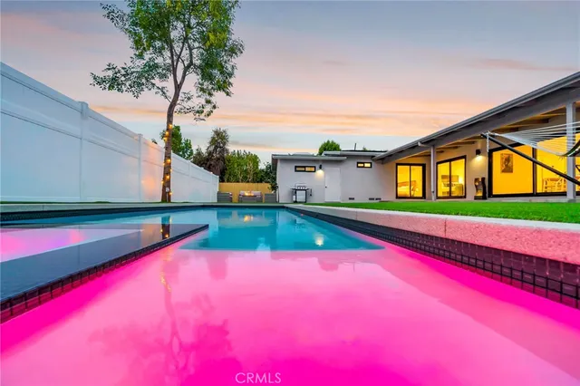 a large kitchen with stainless steel appliances granite countertop a dining table chairs stove and white cabinets