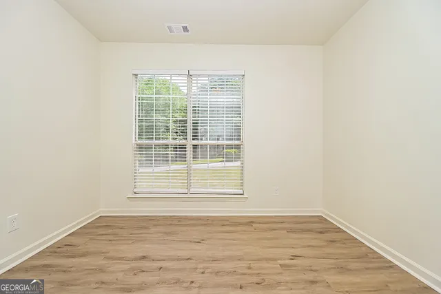 a view of an empty room with wooden floor and a window
