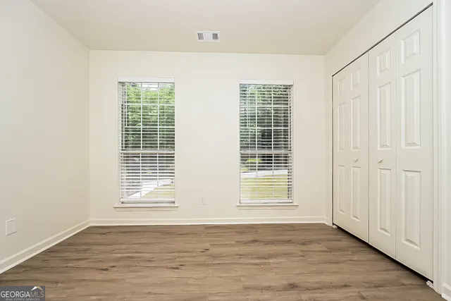 an empty room with wooden floor and windows
