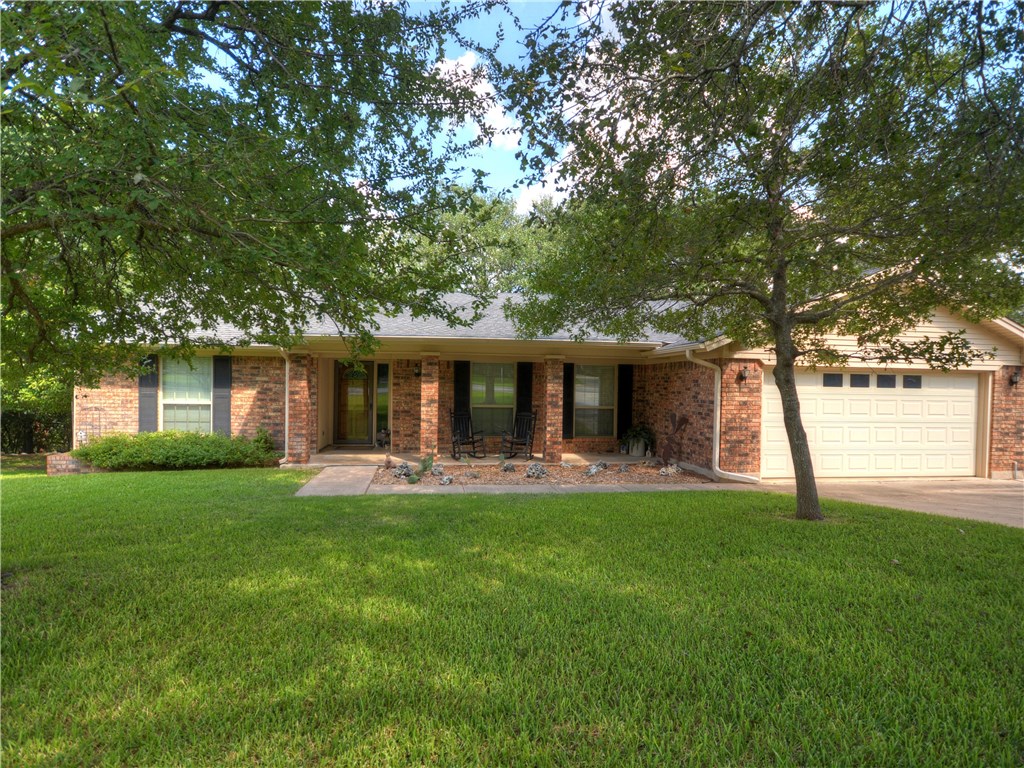 a front view of a house with a garden and trees