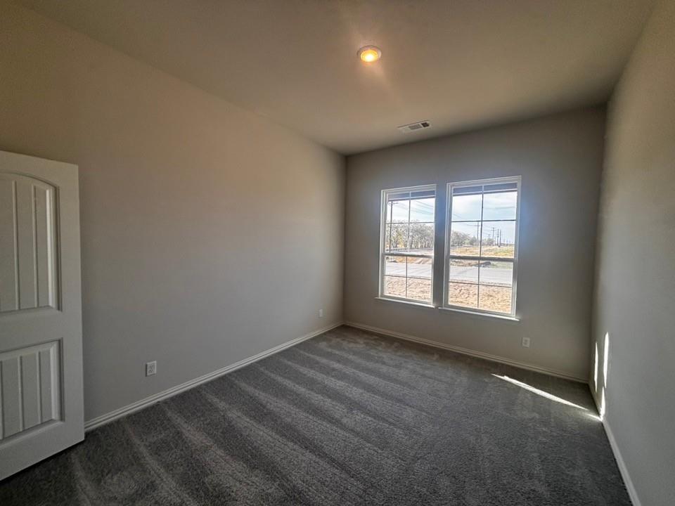 108 Pheasant Run Drive Rhome, TX 76078 - Photo 4 of 14 Neutral wall paint, patterned carpet flooring, recessed ceiling light, white trim windows, and a panel door