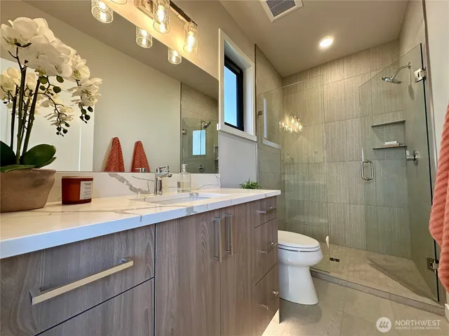 a bathroom with a granite countertop sink a toilet a mirror and shower