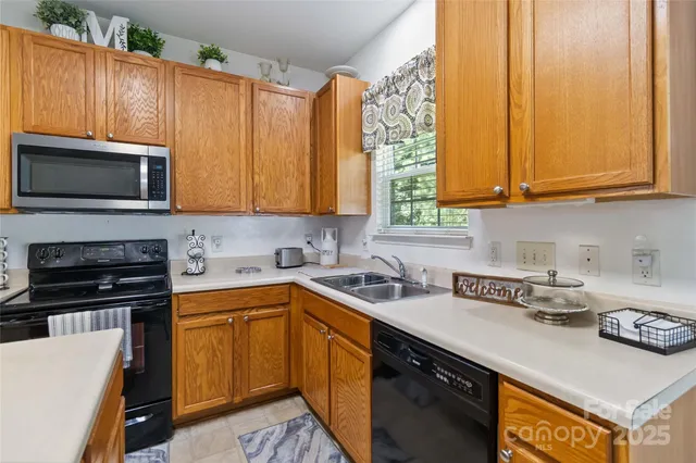a kitchen with stainless steel appliances granite countertop a sink a stove a microwave cabinets and a counter top space