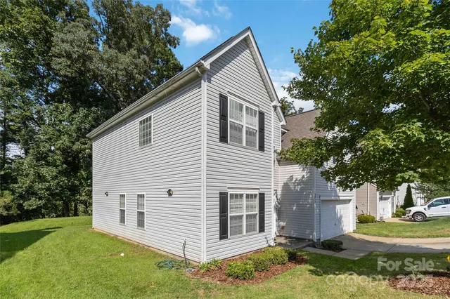 a view of a white house next to a yard with big trees