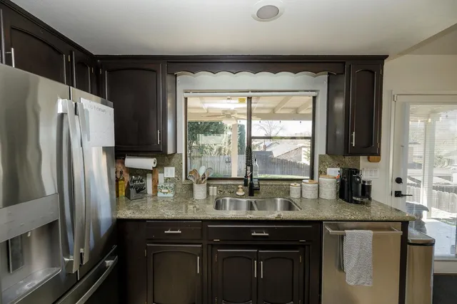 a kitchen with granite countertop a refrigerator a sink and a stove