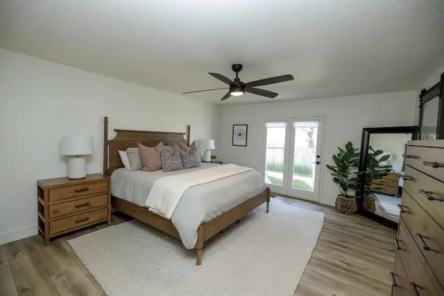 a spacious bedroom with a bed and a potted plant on a dresser