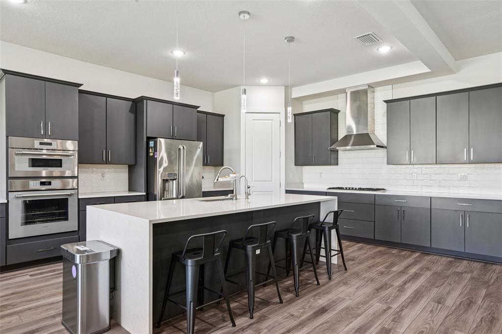 8743 Sanders Tree Loop Wesley Chapel, FL 33545 - Photo 8 of 41 a kitchen with kitchen island granite countertop a table chairs microwave and refrigerator