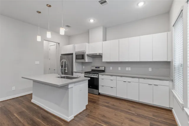 a kitchen with kitchen island granite countertop a sink stove and cabinets